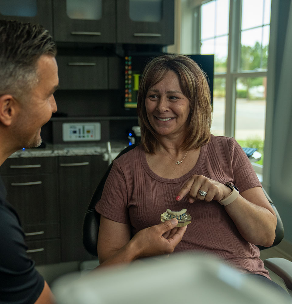 patient and doctor looking and going over full arch dental implant model within the dental center