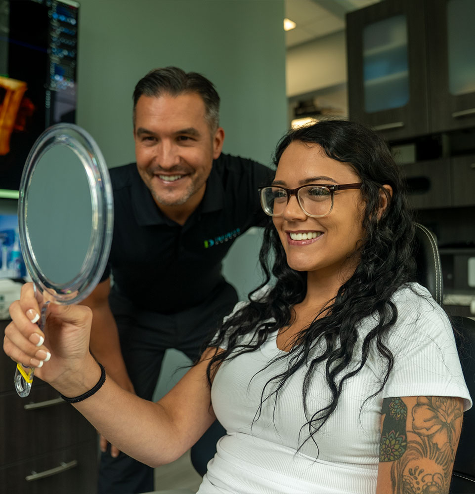 patient and doctor both smiling after patient's dental implant procedure within the dental center