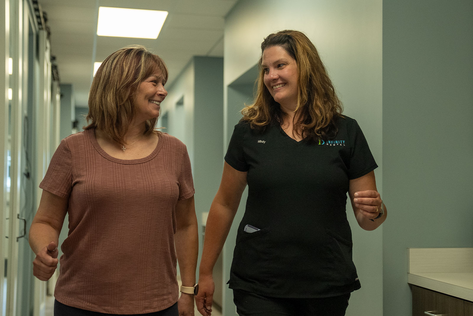 patient and staff member walking through the halls of the dental center both smiling