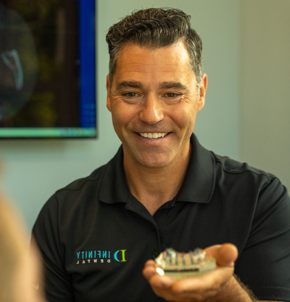 doctor showing patient a full arch dental model within the dental center for their procedure