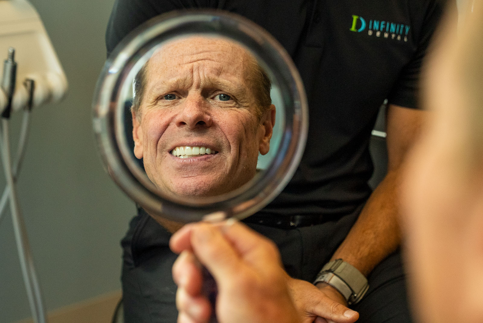 dental patient looking at mirror and smiling brightly after their dental procedure