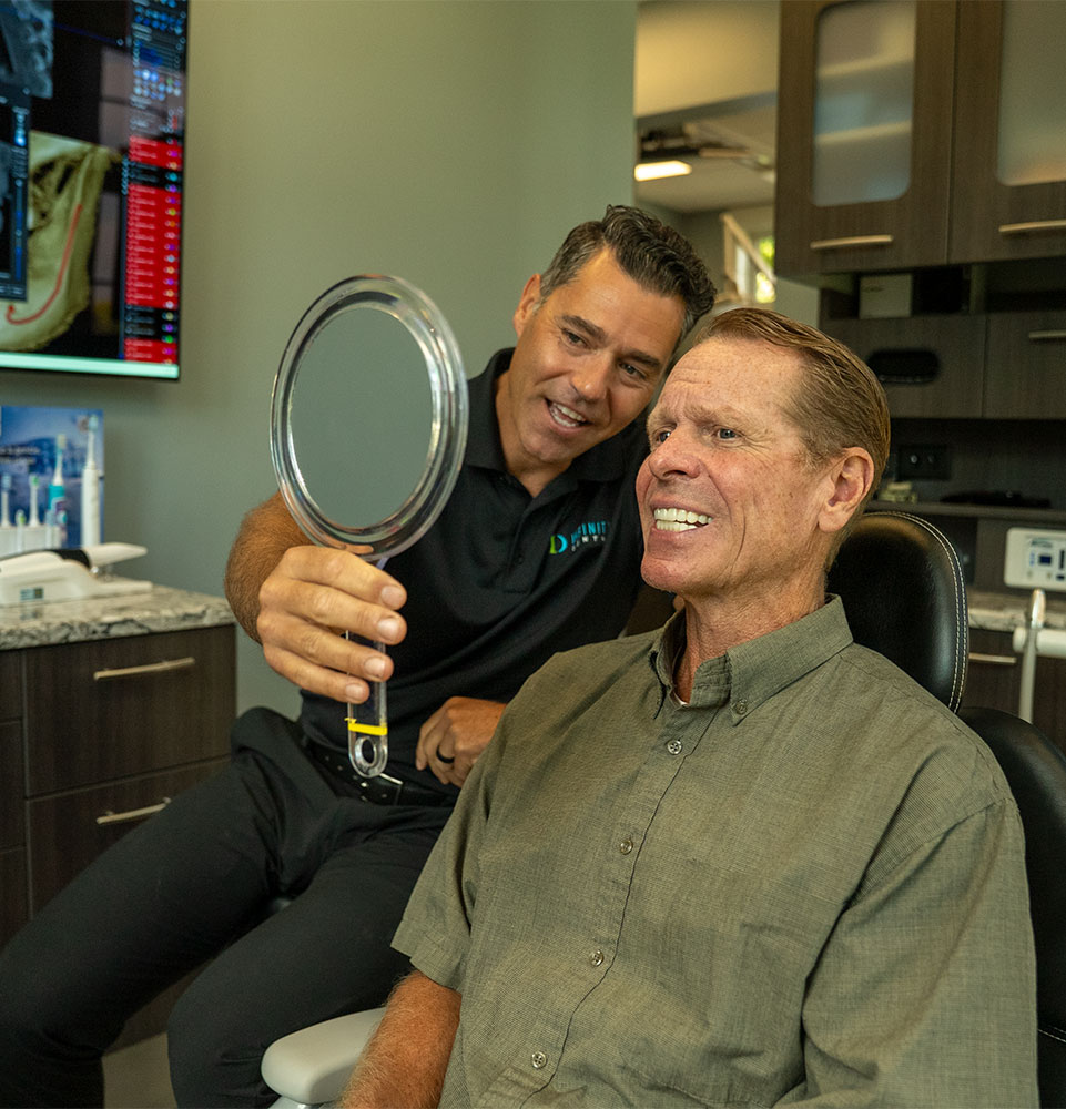 patient being shown in the mirror their smile by doctor within the dental center