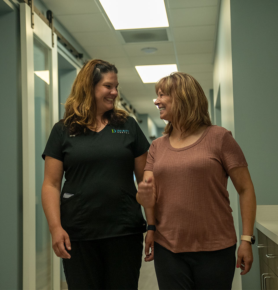 patient and staff member walking down he hall of the dental center both smiling